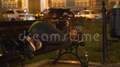 醉汉睡在<strong>垃圾桶</strong>附近城市的长凳上。
