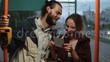 年轻的幸福夫妇在公共交通工具上，在电车上拿着卡片。 男人和女人晚上一起玩。