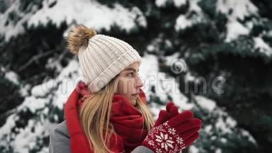 年轻漂亮的女孩穿着温暖的衣服站在圣诞树和温暖的手附近。 慢动作。 肖像