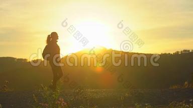 徒步旅行女游客的剪影，带着背包在日落时分在山上徒步旅行。 女旅行者女旅行者