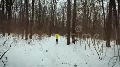 在冬日的白雪覆盖的小路上追踪一个人在森林中奔跑的镜头