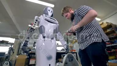 一位工程师在机器人前臂上使用便携式螺丝刀。