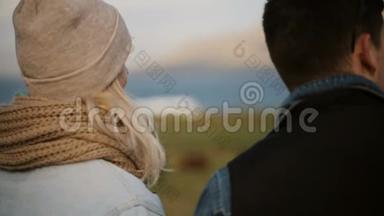 年轻夫妇站在大自然上交谈的背影。 男人和女人欣赏城外的风景。