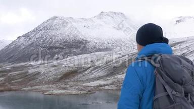 一个带背包的人在<strong>山里</strong>旅行。 他的周围是美丽的山脉和清澈的湖泊。 他的照片