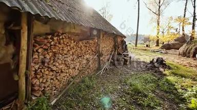 阳光下村庄里的木制谷仓。 谷仓的墙上装满了成堆的劈柴。 秋天