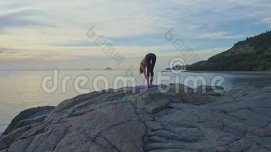 黎明时分，空中观景女孩站在石滩上做瑜伽姿势