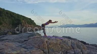 Flycam展示了女孩在黎明时分在海岸弯曲瑜伽姿势