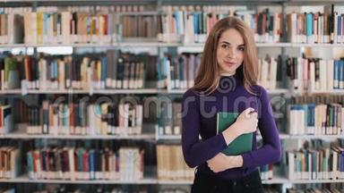 微笑的女学生拿着一本书站在图书馆的<strong>书架前</strong>