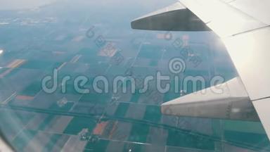 飞机飞过荷兰五彩郁金香美丽的田野，从舷窗俯瞰。 飞机机翼