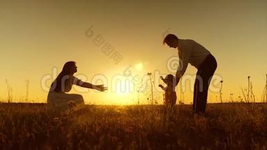 一个小孩子学会和<strong>爸爸妈妈</strong>一起散步，年轻漂亮的家庭在夕阳下和孩子一起在田野里散步，慢动作