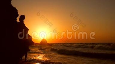 在美丽的金色日落海滩上，年轻女子用手机行走的剪影。 高清慢速运动。 1920x1080。