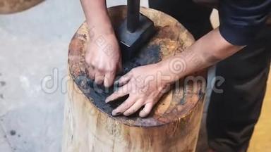 如何制作徽州墨棒系列，第四步，手工艺人在木砧上用大锤敲打烫手的生墨棒