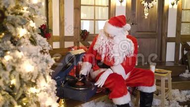 圣诞老人坐在房子附近的圣诞树之间，喝牛奶，吃饼干，听乙烯基的圣诞歌曲