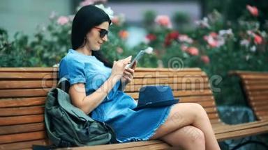 带着<strong>手机</strong>的女游客在温暖的<strong>春天</strong>坐在公园里。