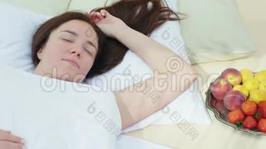 一个年轻的女人睡在一盘水果旁边。 <strong>床</strong>和早餐<strong>浪漫</strong>和蜜月<strong>浪漫</strong>