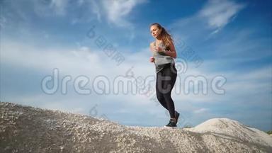 一个<strong>身材好</strong>的年轻女子沿着一座高山上的高石奔跑