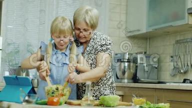 我们一起工作。 六岁的女孩和奶奶一起在厨房做沙拉，玩得很开心。 健康