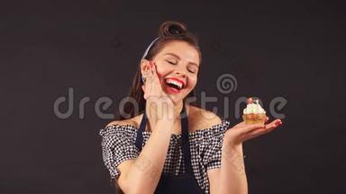 年轻女子<strong>面点</strong>厨师手里拿着纸杯蛋糕对着镜头微笑