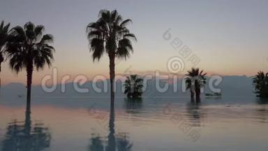 日落时有山、棕榈和游泳池的场景。 土耳其