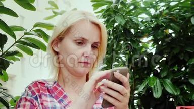 一位年轻女子在咖啡馆的夏季露台上使用智能手机的肖像。 欧洲旅游业-格拉茨市