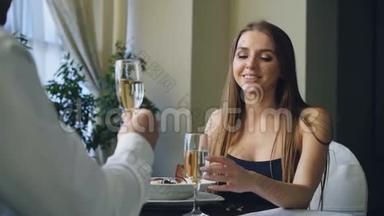女友和男友正在高档餐厅里碰杯，喝香槟，谈浪漫的约会