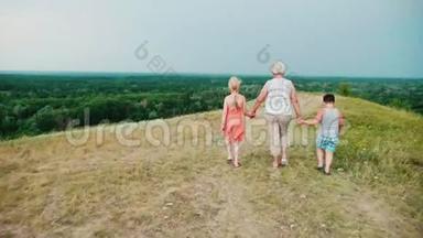 祖母手里拿着两个孙子-一个女孩和一个男孩走过<strong>热闹的</strong>农村。 回去
