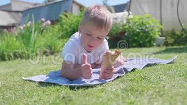 一个小男孩躺在草坪上，高兴地吃冰淇淋。 <strong>炎炎夏日</strong>，冷甜甜点