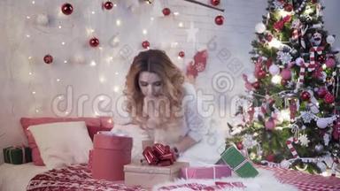 年轻的<strong>美女</strong>坐在圣诞树附近的床上，包上<strong>新年</strong>礼物