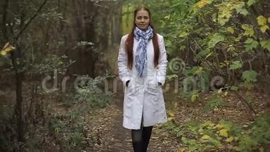 金发白种人<strong>中年妇女</strong>穿着白大褂在秋天公园的阴天散步