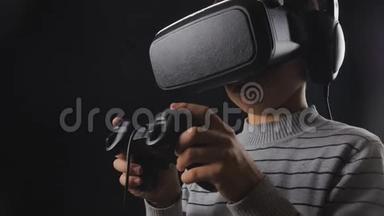 男孩在黑色背景下使用带有耳机和操纵杆的VR耳机显示器进行虚拟现实游戏