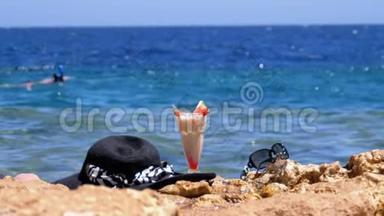 埃及海滩上的热带<strong>鲜榨果汁</strong>、帽子和眼镜架在海边的岩石上
