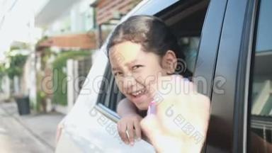 在泰国学生幼儿园，亚洲小女孩在早晨的环境中，微笑着、快乐地在车里做着均匀的手势