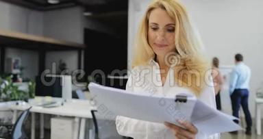 快乐微笑的女老板阅读报告文件从商务团队的吹牛大会中走出来