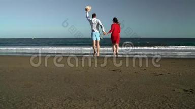 恋爱中的夫妻无忧无虑地跑到海滩上的水里。 西班牙加那利群岛特内里费海岸图片