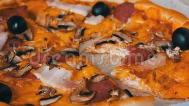 意大利大比萨饼，有黑色橄榄，培根，腊肠和奶酪。 一块比萨饼被咬了