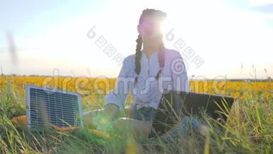可再生能源，女孩用太阳能电池在向日葵上的笔记本电脑上说话，年轻女子用太阳能电池供电