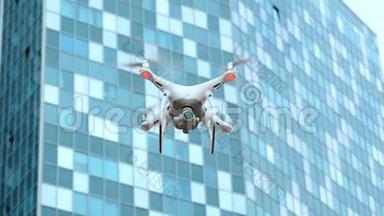 在一座工业商业大厦的背景下，白色现代四翼飞机在城市里飞行和拍摄视频