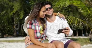 情侣坐在棕榈树下拥抱户外，快乐的微笑男人和女人享受阳光