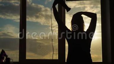 一位中年妇女在日落时分烘干吹风机。