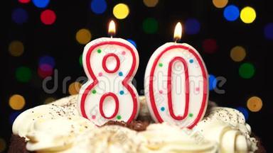 蛋糕上的80号-80岁生日蜡烛燃烧-最后吹灭。彩色模糊背景