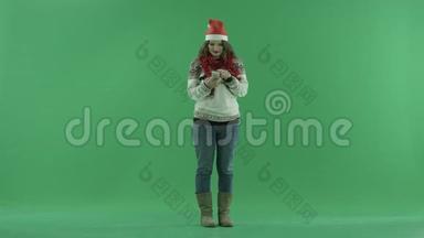 兴奋的年轻女子戴着圣诞帽一边站着一边在智能手机上<strong>讲话</strong>，<strong>背景</strong>上的彩色钥匙