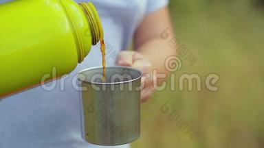 一个女人把热水瓶里的热茶倒进杯子里。