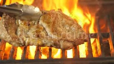厨师用火钳转动烤架上的猪肉牛排，看它炸了多少，视频是特写的