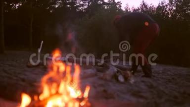 年轻人在篝火旁砍柴。 4K，慢动作。