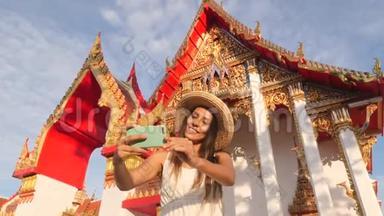 年轻的高加索旅游妇女在<strong>泰国佛寺</strong>用手机拍摄自拍照片。 <strong>泰国</strong>普吉岛。 4K