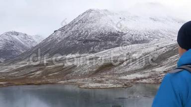 一个带背包的人在<strong>山里</strong>旅行。 他的周围是美丽的山脉和清澈的湖泊。 他拍了照片