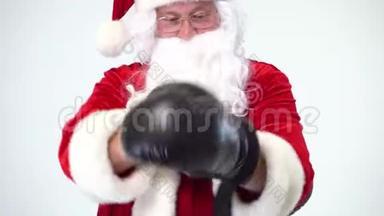 圣诞节。 白色背景上的圣诞老人戴着黑色拳击手套，完成了拳击。 拳击，拳击手。 恐惧