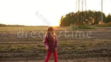 年轻的白种人女孩跳着，看着路边。 在田野里跳舞，农村场景，秋天的日落。 慢点