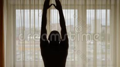 早晨窗帘前的人举起双手，伸伸懒腰. 成人和带窗帘的大窗户。