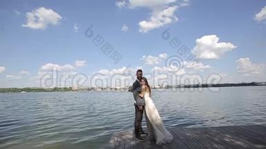 一对年轻漂亮的新婚夫妇站在湖边。 结婚纪念日。 慢动作